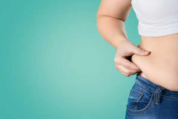 Image of woman pinching her love handles to show weight gain Brent